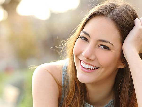 Benefits of Sleep Article Photo - Young woman smiling.