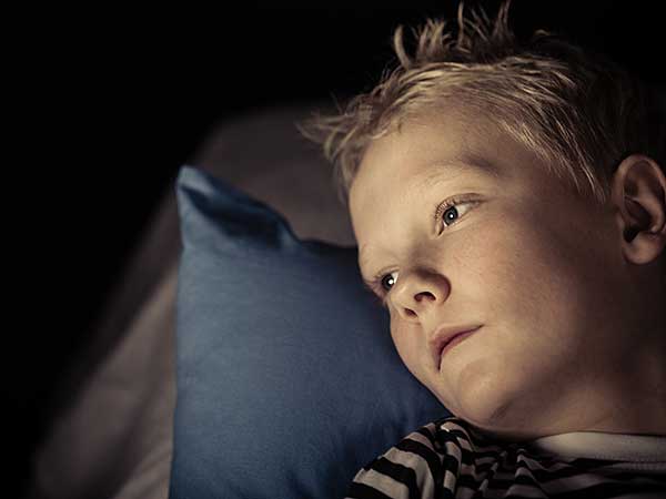 Little boy with childhood insomnia laying on pillow.
