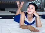 Lady in blue and white dress laying on mattress in store.