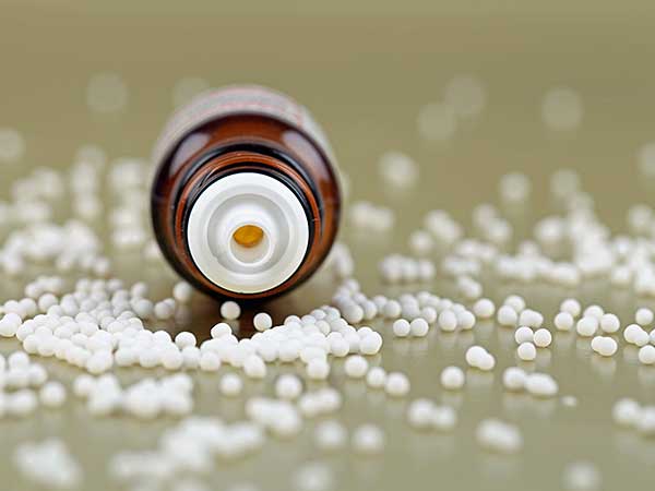 Brown medicine bottle laying in homeopathic sugar balls.