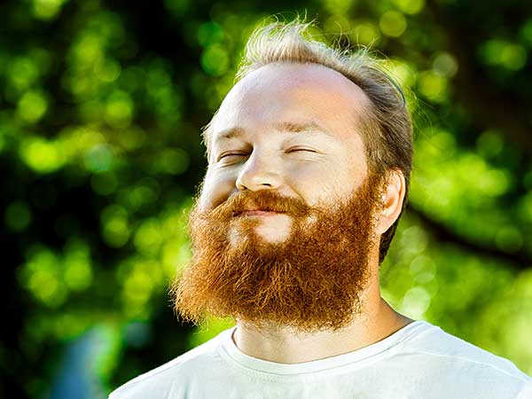 Photo for How To Sleep Better Article featuring man with red beard getting sunshine outdoors.
