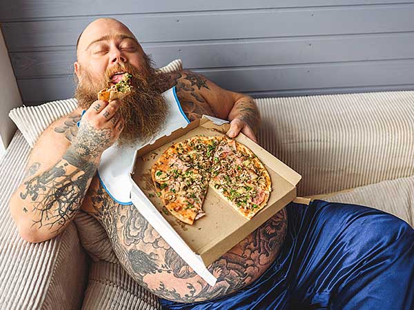 Overweight man eating pizza.